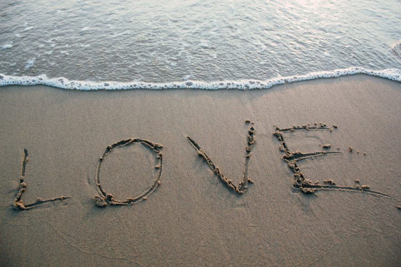 Love written in sand by the ocean