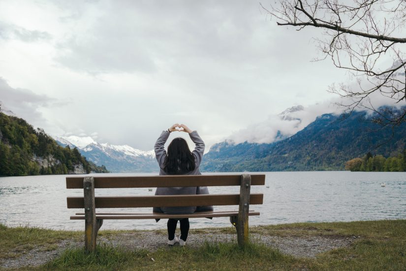 woman sitting on park bench looking at mountain view